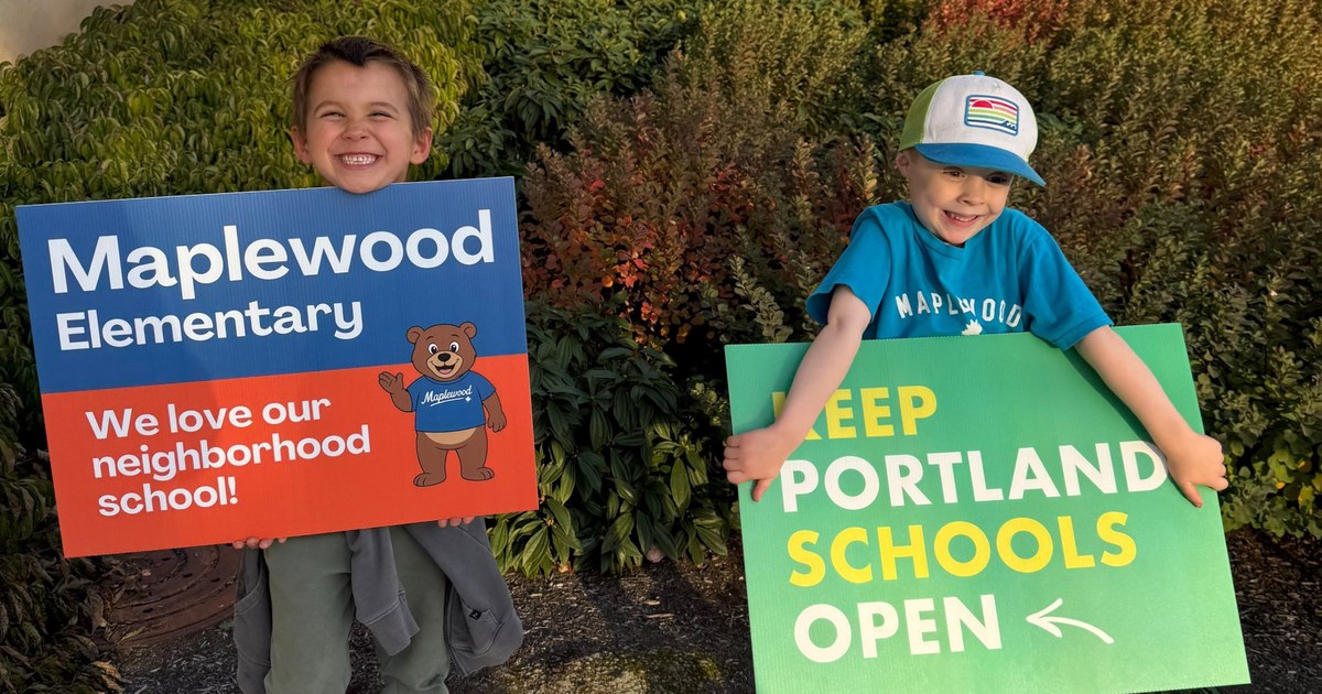 Two Maplewood students smile outside Benson High School holding signs that read “Maplewood Elementary: We love our neighborhood school!” and “Keep Portland Schools Open.”